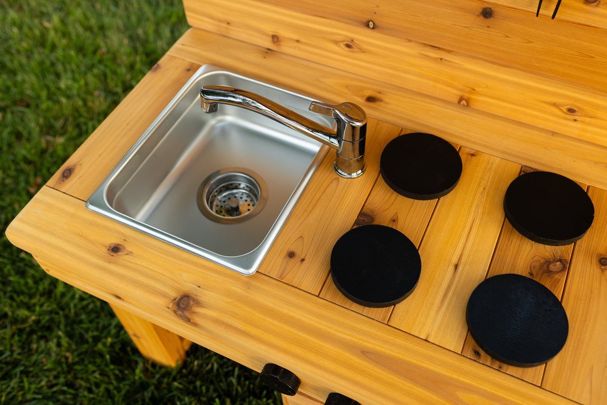 Cedar outdoor mud kitchen by Noble Wooden Toys with oven, stovetop, working faucet and 2 centred stainless steel sinks