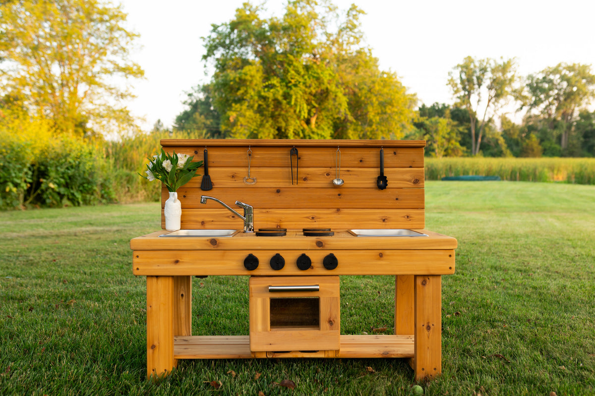 Cedar outdoor mud kitchen by Noble Wooden Toys with oven, stovetop, working faucet and 2 centred stainless steel sinks