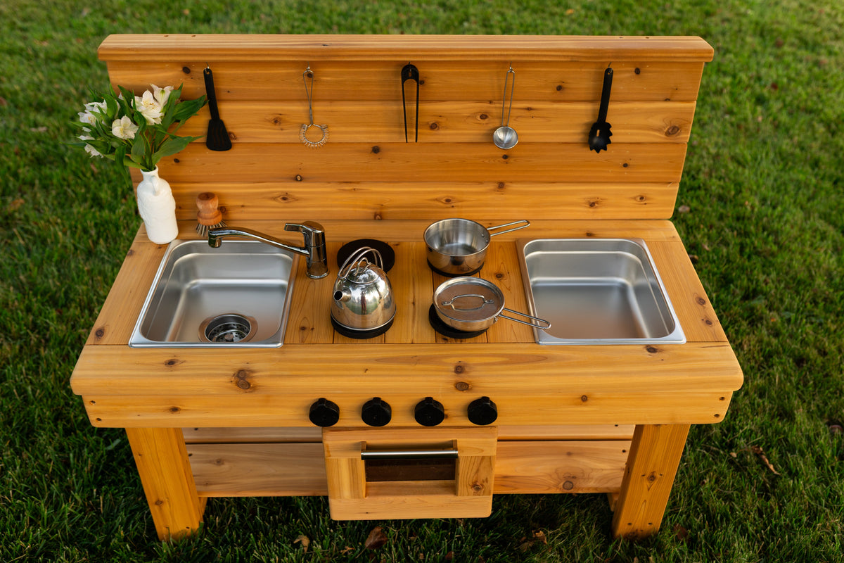 Cedar outdoor mud kitchen by Noble Wooden Toys with oven, stovetop, working faucet and 2 centred stainless steel sinks