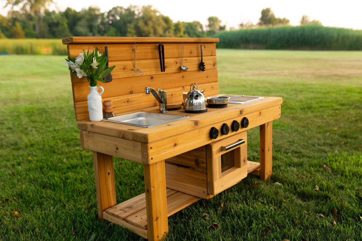 Cedar outdoor mud kitchen by Noble Wooden Toys with oven, stovetop, working faucet and 2 centred stainless steel sinks