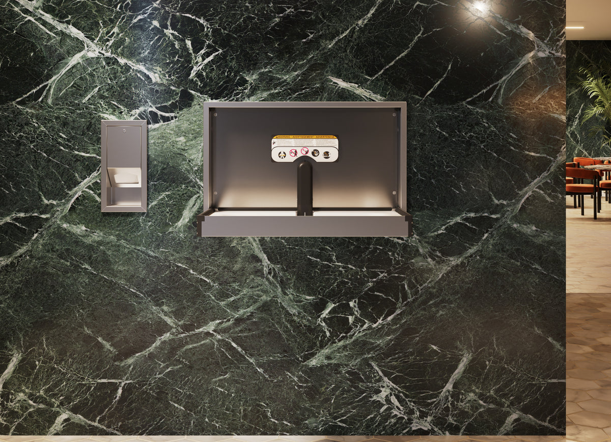 Distributeur de protège-tables encastré en inox installé à côté d'une table à langer murale ouverte