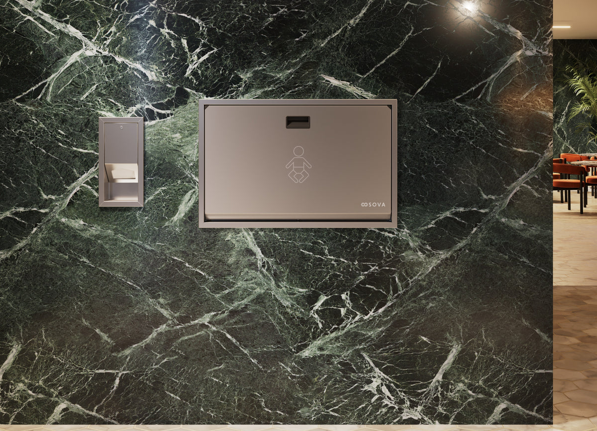 Distributeur de protège-tables encastré en inox installé à côté d'une table à langer murale fermée